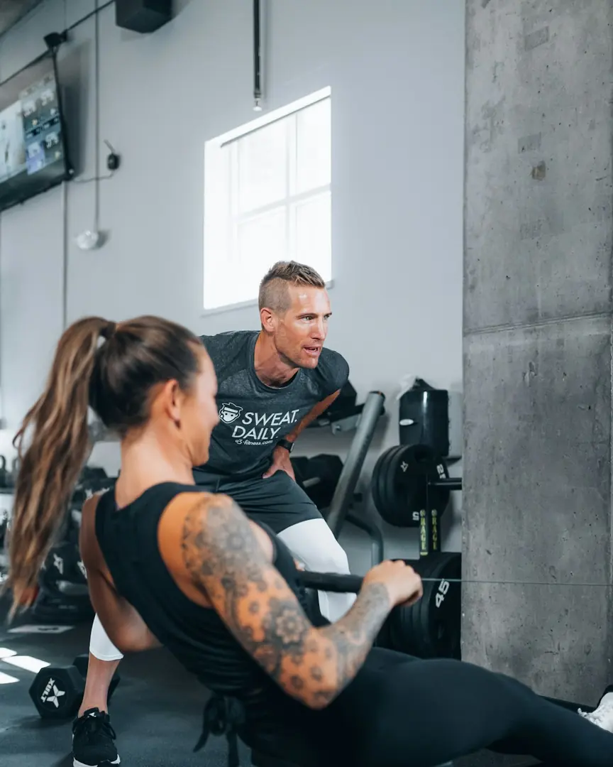 Personal trainer orientando uma aluna em um aparelho de musculação
